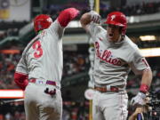 Philadelphia Phillies' J.T. Realmuto, right, celebrates his solo homer with Philadelphia Phillies Bryce Harper during the 10th inning in Game 1 the World Series on Friday.