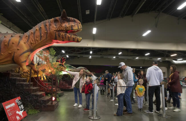Children wait in line with their families for a chance to ride dinosaurs. There were also bouncy houses, a jeep ride and a fossil dig for children.