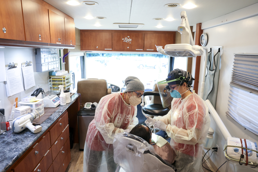 Gloria Sanchez Keeth, Clinic manager with Medical Teams International, and dentist Thien-Y Hoang work on a patient inside the Mobile Dental Clinic during a community wellness event at Chemeketa Community College in Salem, Ore. on Saturday, Oct.
