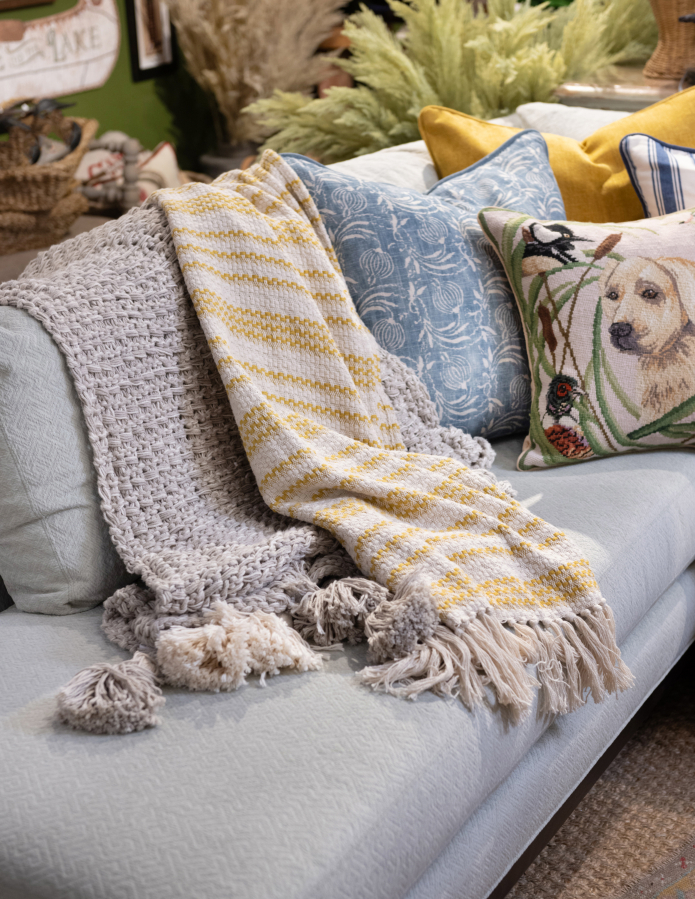 Two layered throw blankets make for a snuggly and inviting couch display.