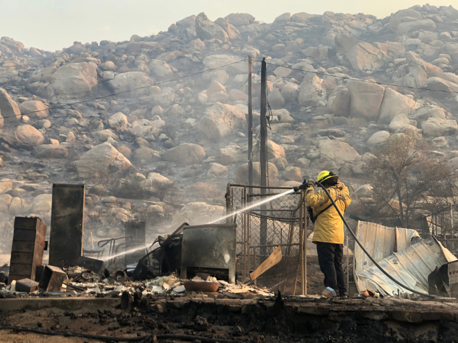 A firefighter on Sept. 6 extinguishes hot spots where a home once stood on Gibbel Road near Hemet, Calif.