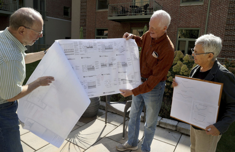 Art Spooner, from left, Paul Dickerson, and Elaine Johnson ? who have community solar in the condo building ? show charts of their electricity costs outside their Oak Park building on Sept. 29, 2022.
