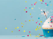 Birthday party background with birthday cupcake, celebration sparkler and colorful falling confetti