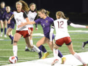Columbia River's Ivy Henderson, center, tries to weave in between Bellingham defenders Genevieve Blum, left, and Katura Curtis, right, in a 2A state playoff match Wednesday.