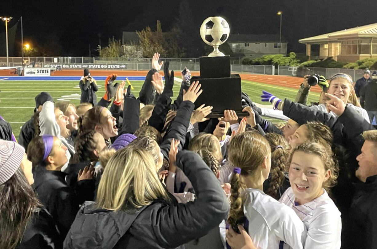Columbia River players and coaches celebrate with the Class 2A state soccer championship trophy after the Rapids defeated Sehome 1-0 on Saturday in Shoreline.