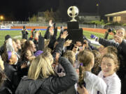 Columbia River players and coaches celebrate with the Class 2A state soccer championship trophy after the Rapids defeated Sehome 1-0 on Saturday in Shoreline.