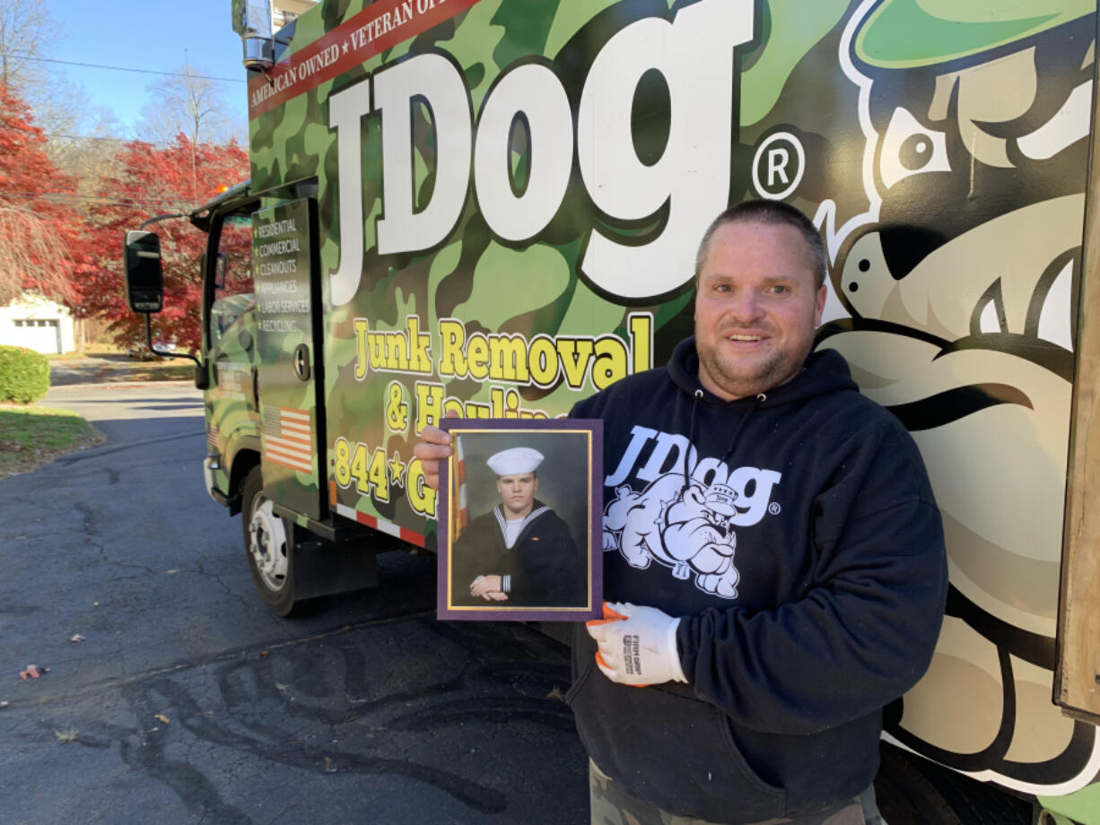 Military veteran Dustin Grady, of Guilford, holds a photo of himself from when he served in the U.S. Navy in the mid-2000s. Grady, now 38, said he has struggled to find a niche in the civilian workforce. He is now working for JDog Junk Removal and Hauling, a company that seeks to hire veterans. (Kenneth R.