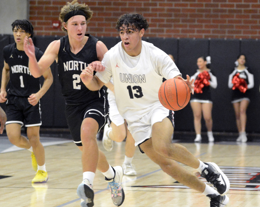 Union's Yanni Fassilis, right, dribbles up the floor while being closely guarded by North Kitsap's Mason Chmielewski in the Titans' season opener on Saturday, Nov. 26, 2022, at Union High School.