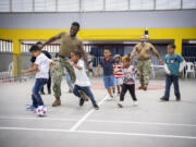 Hospital Corpsman Third Class Joshua Soske, from La Center, and Hospital Corpsman Third Class Lou-Shane Daley, from St. Catherine, Jamaica, play soccer with children at the Sports Coliseum of Combat and Gymnastics in Cartagena, Colombia. (U.S.