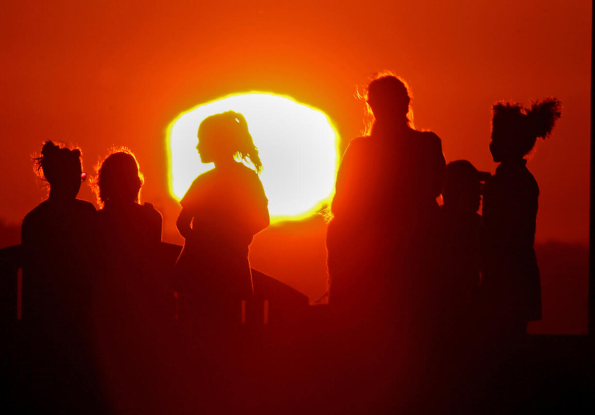 A blazing sun silhouettes visitors to Signal Hill after another hot day across Southern California, on Sept. 1.