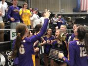 Columbia River's Sofie Worden holds the state championship trophy as her teammates celebrate after the Class 2A volleyball state championship match against Ridgefield on Saturday, Nov. 19, 2022, in Yakima.