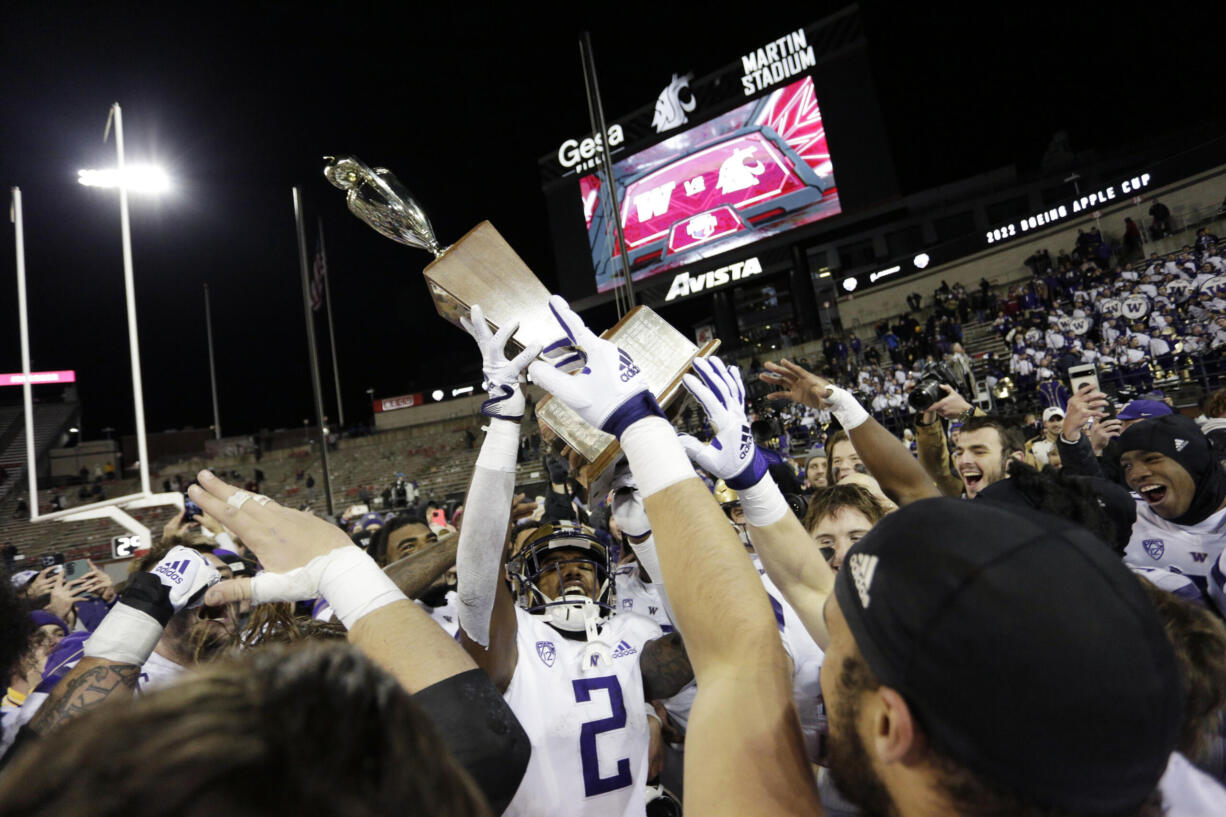 Washington players celebrate with the Apple Cup Trophy after their 51-33 win against Washington State in an NCAA college football game, Saturday, Nov. 26, 2022, in Pullman, Wash.
