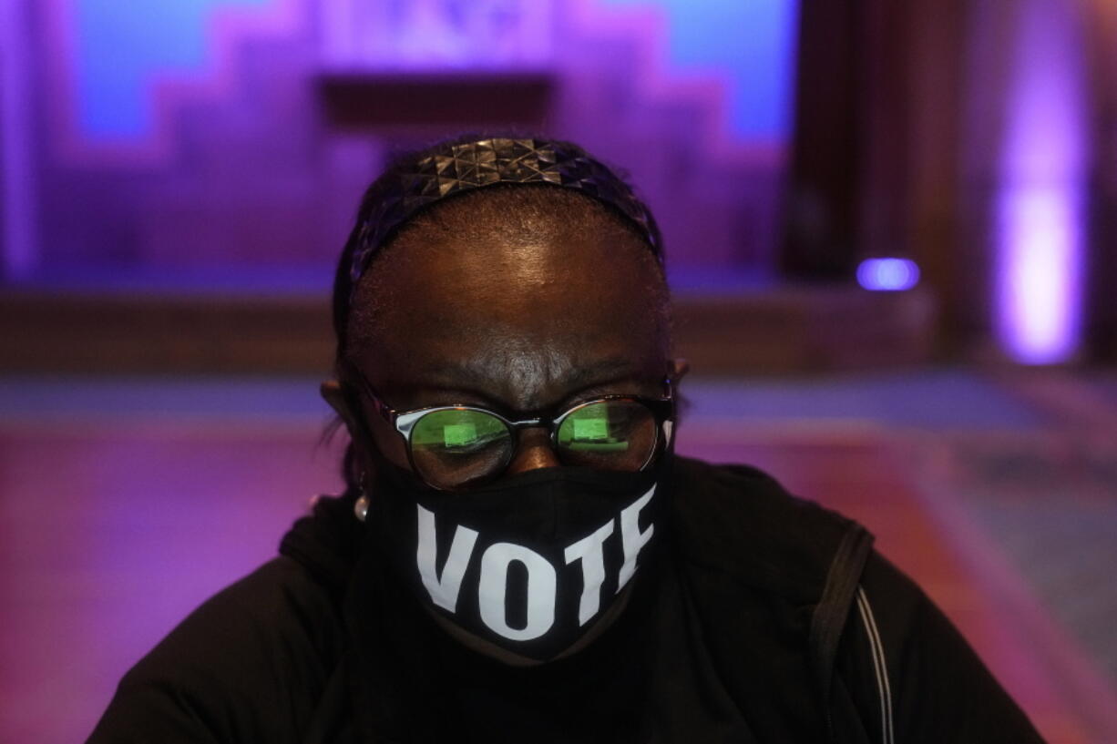 A poll worker wears a "vote" mask as they check in voters on Election Day, Tuesday, Nov. 8, 2022, in Atlanta.