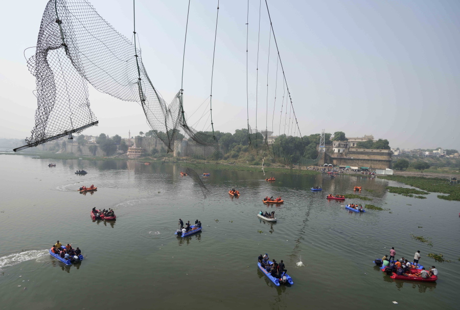Rescuers on boats search in the Machchu river next to a cable bridge that collapsed on Sunday in Morbi town of western state Gujarat, India, Tuesday, Nov. 1, 2022. A century-old cable suspension bridge collapsed into the river Sunday evening, sending hundreds plunging in the water in one of the country's worst accidents in years.