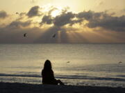 A woman meditates on the beach in Miami Beach, Fla.