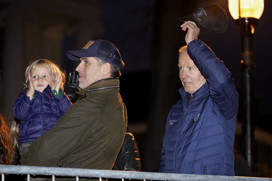 President Joe Biden removes his hat as he is recognized during the annual Christmas Tree Lighting ceremony in Nantucket, Mass., Friday, Nov. 25, 2022. Hunter Biden holds his son Beau Biden at left.