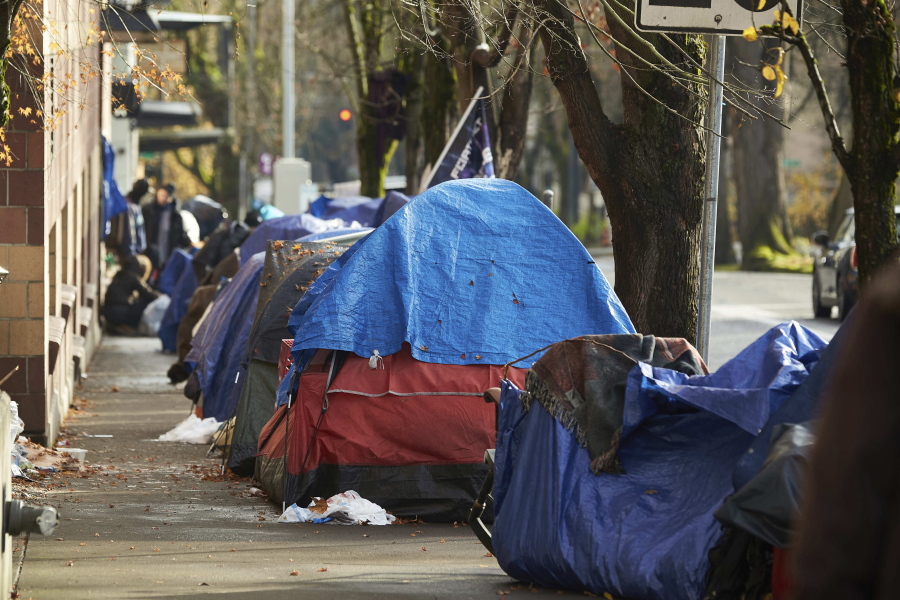 FILE - Tents line the sidewalk on SW Clay Street in Portland, Ore., on Dec. 9, 2020. City Council members have pushed back a vote on a disputed budget measure that would fund the creation of designated camping areas for homeless people. The move came after a heated council meeting on Thursday, Nov. 17, 2022, in which residents expressed strong opposition in public testimony. The proposed budget would allocate $27 million to build a network of large, outdoor sites where homeless people will be allowed to camp.