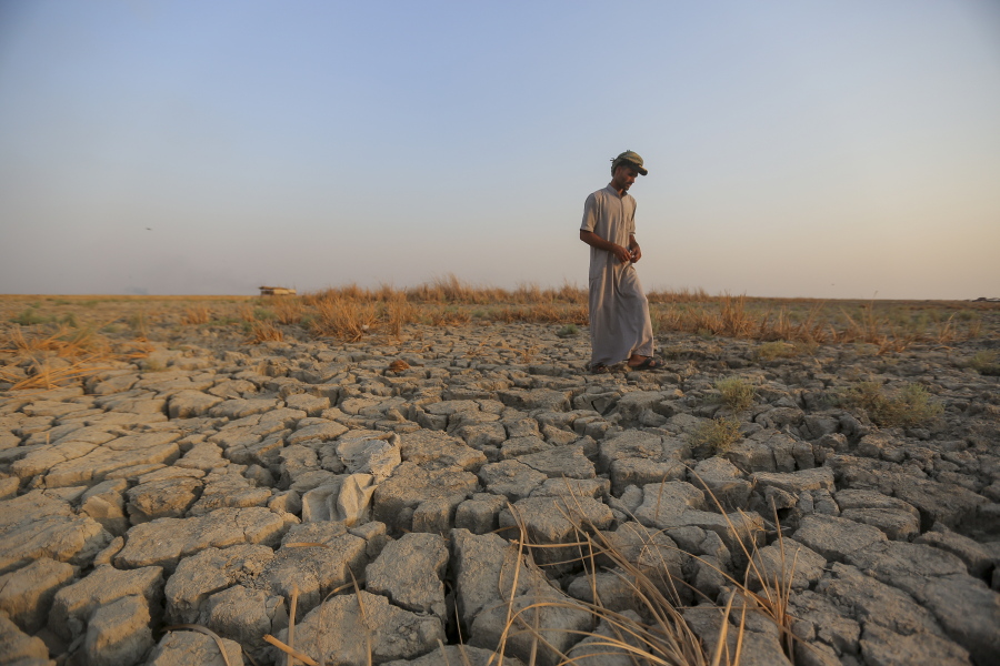 A fisherman walks across a dry patch of land in the marshes of southern Iraq which has suffered dire consequences from back to back drought and rising salinity levels, in Dhi Qar province, Iraq, Friday Sept. 2, 2022.