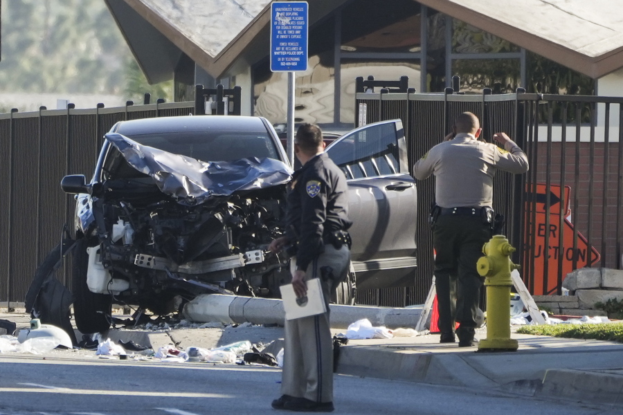 Two investigators stand next to a mangled SUV that struck Los Angeles County sheriff's recruits in Whittier, Calif., Wednesday, Nov. 16, 2022. The vehicle struck several Los Angeles County sheriff's recruits on a training run around dawn Wednesday, some were critically injured, authorities said.  (AP Photo/Jae C.