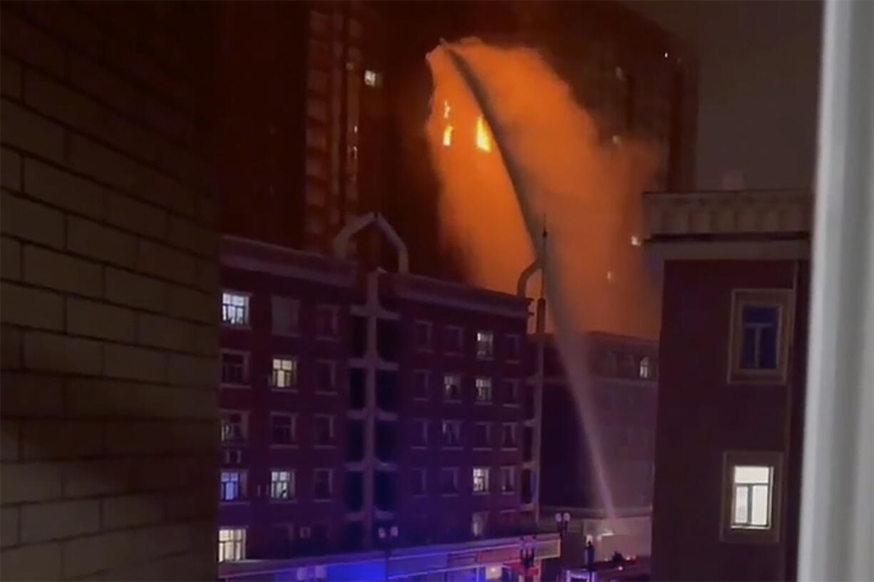 In this image taken from video, firefighters spray water on a fire at a residential building in Urumqi in western China's Xinjiang Uyghur Autonomous Region, Thursday, Nov. 24, 2022. A fire in an apartment building in northwestern China's Xinjiang region has killed several people and injured others, authorities said Friday, in the second major fire accident in the country this week.