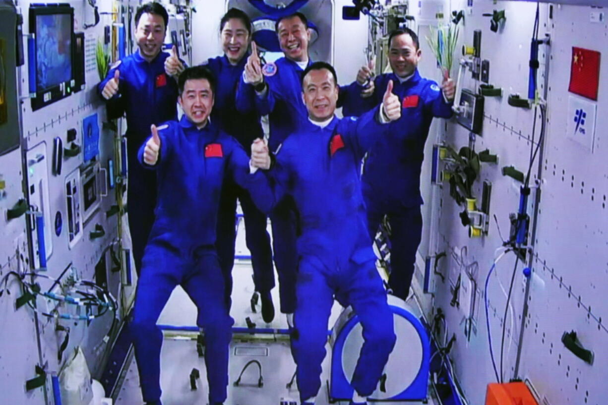 In this photo released by Xinhua News Agency, an image captured off a screen at the Jiuquan Satellite Launch Center in northwest China shows the Shenzhou-15 and Shenzhou-14 crew taking a group picture with their thumbs up after a historic gathering in space on Wednesday, Nov. 30, 2022. Three Chinese astronauts docked early Wednesday with their country's space station, where they will overlap for several days with the three-member crew already onboard and expand the facility to its maximum size.