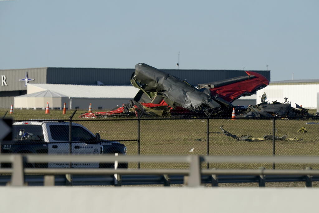 An emergency vehicle sits near debris from two planes that crashed during an airshow at Dallas Executive Airport, Saturday, Nov. 12, 2022.