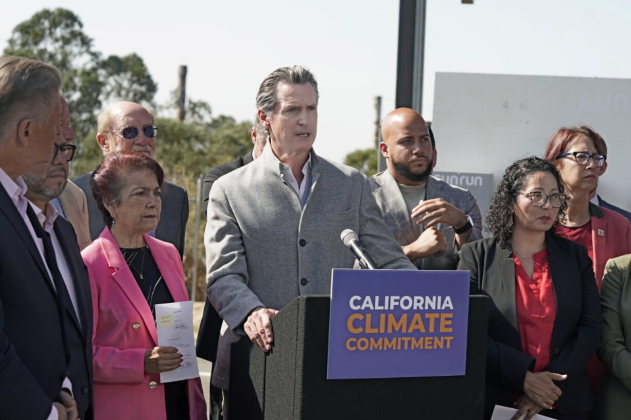 FILE - Gov. Gavin Newsom, center, is flanked by state lawmakers while discussing the package of legislation he signed that accelerates the climate goals of the nation's most populous state, at Mare Island in Vallejo, Calif., Friday, Sept. 16, 2022. Newsom opposes Proposition 30, which would raise taxes on people making more that $2 million to pay for electric vehicle infrastructure and firefight resources.