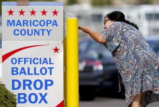 FILE - A voter drops off her ballot at a drop box, Nov. 7, 2022, in Mesa, Ariz. Fears of aggressive poll watchers sowing chaos at polling stations or conservative groups trying to intimidate votes didn't materialize on Election Day as many election officials and voting rights experts had feared. Voting proceeded smoothly across most of the U.S., with a few exceptions of scattered disruptions.