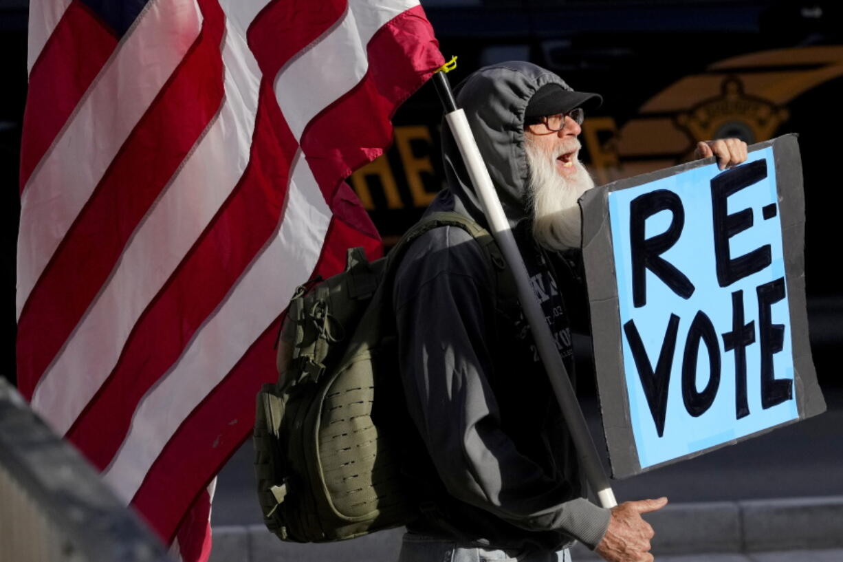FILE - A man protests outside the Maricopa County Board of Supervisors auditorium prior to the board's general election canvass meeting, Nov. 28, 2022, in Phoenix. Worries that rogue county officials could undermine election results by refusing to certify them have lessened significantly in the wake of the midterms, with a lone Arizona county as the exception. Still, baseless attacks on the accuracy of the election by Republican county officials and angry members of the public already are raising concerns about for 2024, when local commissions will be asked to certify the results in a presidential race.