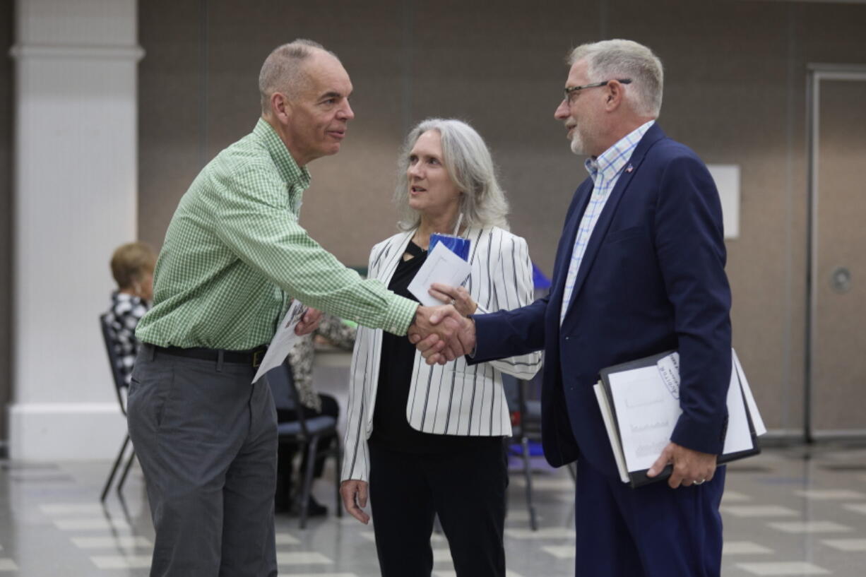 FILE - Paddy McGuire, Democrat incumbent Mason County auditor, left, shakes hands with his election opponent Republican Steve Duenkel, right, before a candidate forum, Oct. 13, 2022, in Shelton, Wash. Between is Mason County Commissioner Sharon Trask.