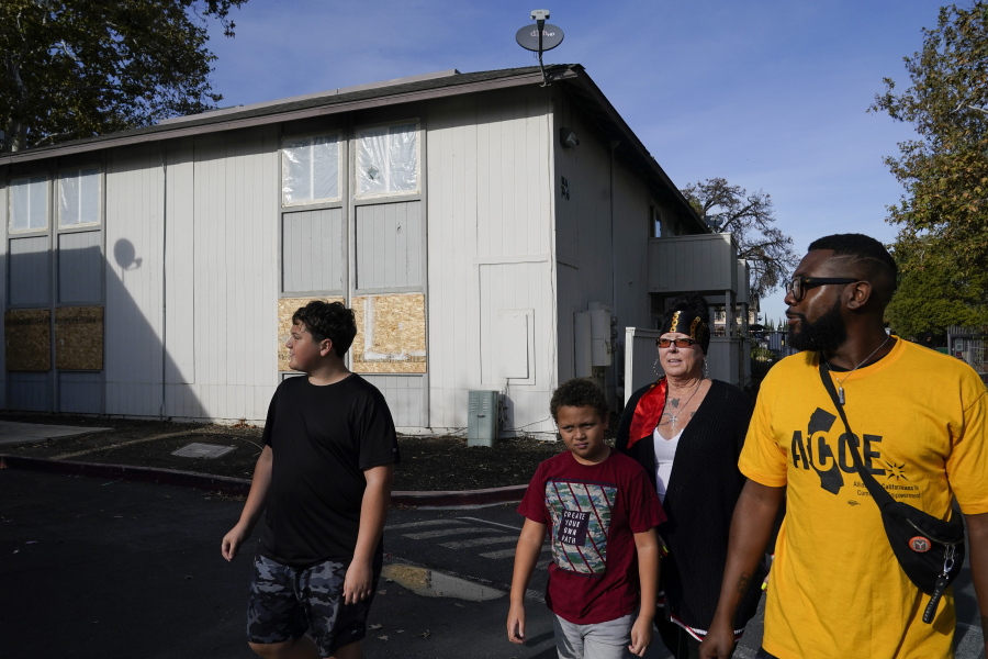 Kim Carlson, third from left, her two grandsons and community organizer Devin Williams, right, walk around the Delta Pines apartment complex, Friday, Nov. 4, 2022, in Antioch, Calif. Despite a landmark renter protection law approved by California legislators in 2019, tenants across the country's most populous state are taking to ballot boxes and city councils to demand even more safeguards. They want to crack down on tenant harassment, shoddy living conditions and unresponsive landlords that are usually faceless corporations. (AP Photo/Godofredo A.