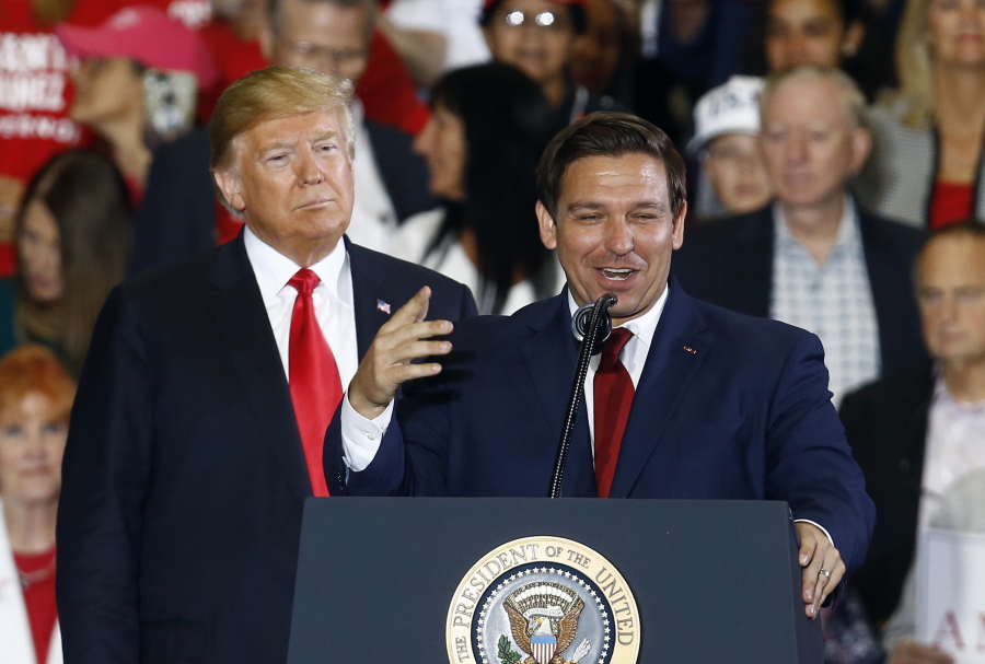FILE- In this Nov. 3, 2018 file photo President Donald Trump stands behind gubernatorial candidate Ron DeSantis at a rally in Pensacola, Fla.