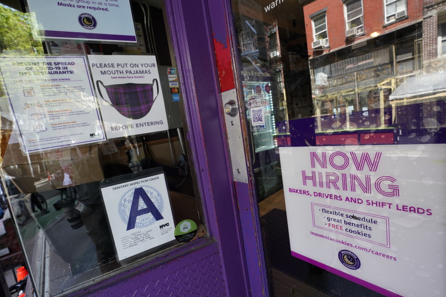 FILE - In this May 4, 2021 file photo, a signs announcing they are hiring hangs in the window of a restaurant in the Greenwich Village neighborhood of Manhattan in New York. Starting this week, job-seekers in New York City will have access to a key piece of information: how much money they can expect to earn for an advertised opening.