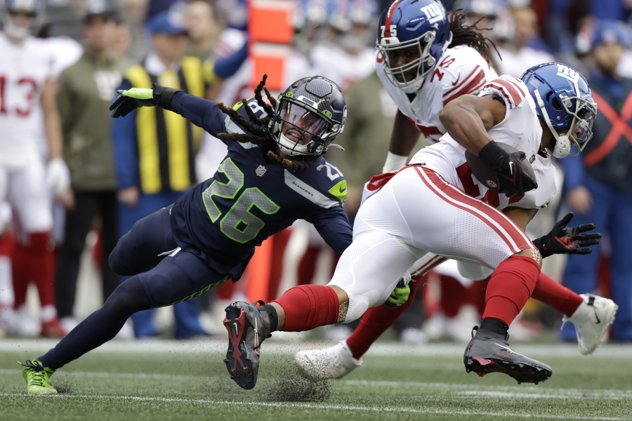 New York Giants running back Saquon Barkley, right, runs against Seattle Seahawks safety Ryan Neal during the first half of an NFL football game in Seattle, Sunday, Oct. 30, 2022.