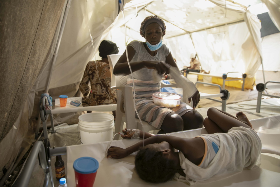 A woman uses a towel to swat flies away from her daughter stricken with cholera, at a clinic run by Doctors Without Borders in Port-au-Prince, Haiti, Friday, Nov. 11, 2022.
