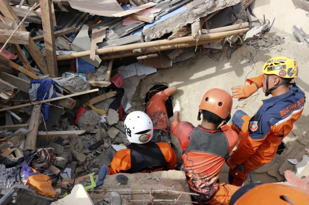 Rescuers search for victims under the rubble of a building collapsed during Monday's earthquake in Cianjur, West Java, Indonesia, Wednesday, Nov. 23, 2022. More rescuers and volunteers were deployed Wednesday in devastated areas on Indonesia's main island of Java to search for the dead and missing from an earthquake that killed hundreds of people.