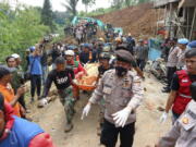 Rescuers carry the body of a victim recovered from under the rubble at a village affected by an earthquake-triggered landslide in Cianjur, West Java, Indonesia, Tuesday, Nov. 22, 2022. The earthquake has toppled buildings on Indonesia's densely populated main island, killing a number of people and injuring hundreds.
