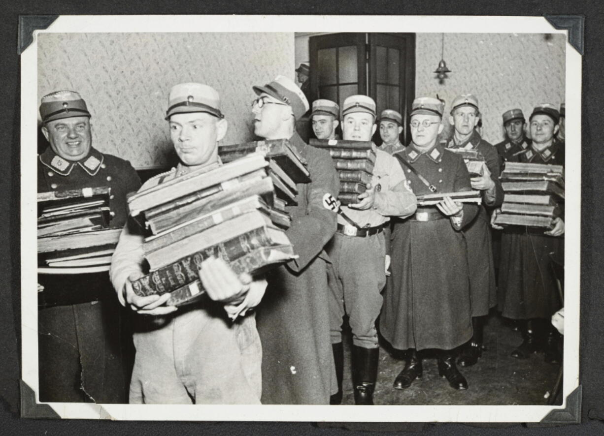 This photo released by Yad Vashem, World Holocaust Remembrance Center, shows German Nazis carry Jewish books, presumably for burning, during Kristallnacht intake most likely in the town of Fuerth, Germany on Nov. 10, 1938. The photos were taken by Nazi photographers during the pogrom in the city of Nuremberg and the nearby town of Fuerth. They wound up in the possession of a Jewish American serviceman who served in Germany during World War II. His descendants,donated the album to Yad Vashem.