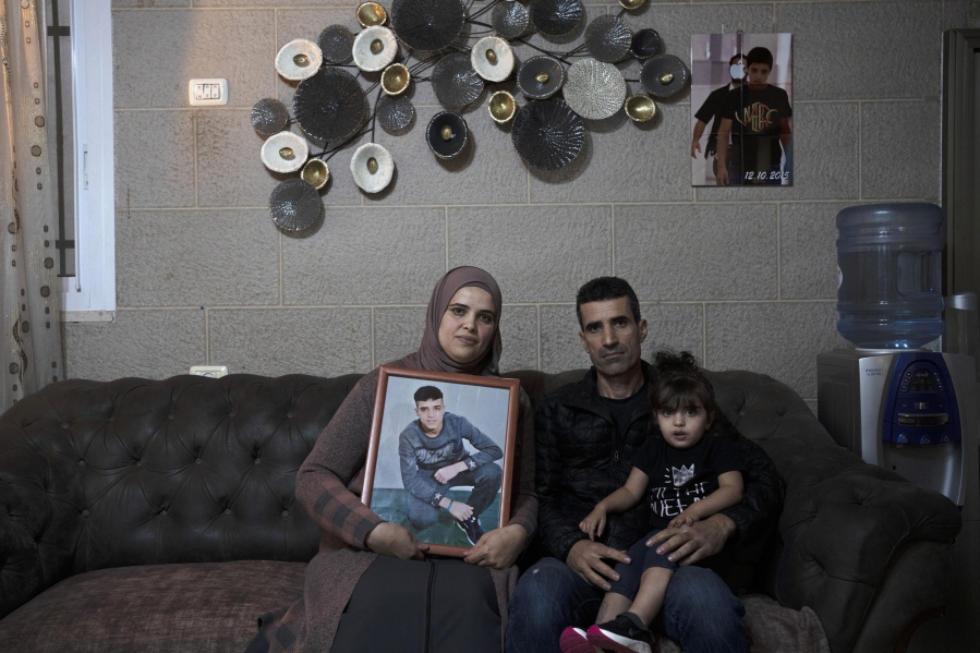 Maysoon, left, and Saleh Manasra, parents of Ahmad Manasra, who has been imprisoned by Israel since he was 13 when he was was convicted of attempted murder and sentenced to nine and a half years in prison, after his older cousin stabbed two Israelis, pose for a portrait with their daughter, Sham, in their home in east Jerusalem, Tuesday, Nov. 8, 2022. The 13 year-old Palestinian boy, whose case became a lighting rod for the Israeli-Palestinian conflict seven years ago, is now a man languishing in solitary confinement and struggling with schizophrenia. This week, Israel's Supreme Court will decide on an appeal for his early release.