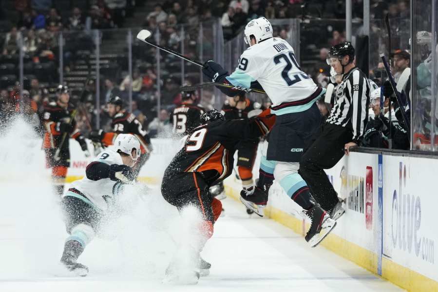 Seattle Kraken's Vince Dunn (29) leaps to avoid a check from Anaheim Ducks' Sam Carrick (39) during the first period of an NHL hockey game Sunday, Nov. 27, 2022, in Anaheim, Calif. (AP Photo/Jae C.