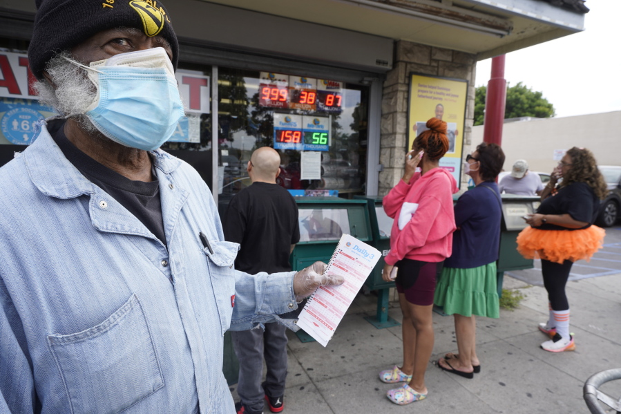Philip Smith, wears a face mask and gloves as he lines up to purchase his lottery tickets for the Powerball lottery at the Blue Bird Liquor store in Hawthorne, Calif., Monday, Oct. 31, 2022. The jackpot for Monday night's drawing soared after no one matched all six numbers in Saturday night's drawing. It's the fifth-largest lottery jackpot in U.S. history.