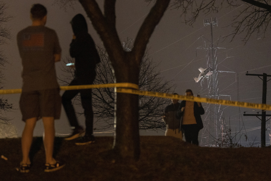People observe a small plane resting on live power lines after crashing, Sunday, Nov. 27, 2022, in Montgomery Village, a northern suburb of Gaithersburg, Md.