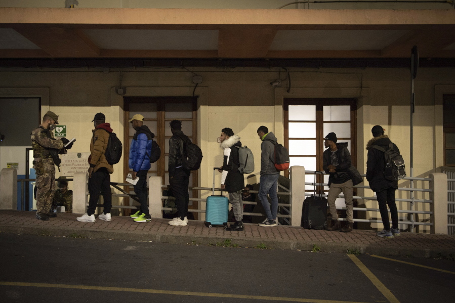 Migrants line up to be checked by Italian authorities at the Italian French border of Ventimiglia, Italy, Saturday, Nov. 12, 2022.