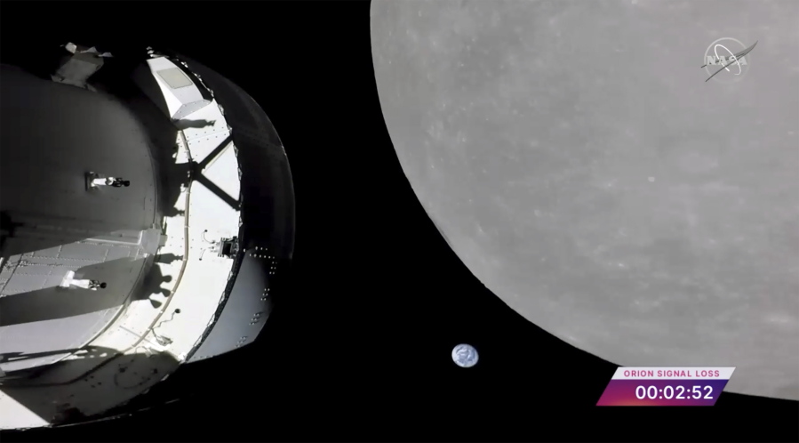 This screengrab from NASA TV shows NASA's Orion capsule, left, nearing the moon, right, Monday, Nov. 21, 2022. At center is earth.