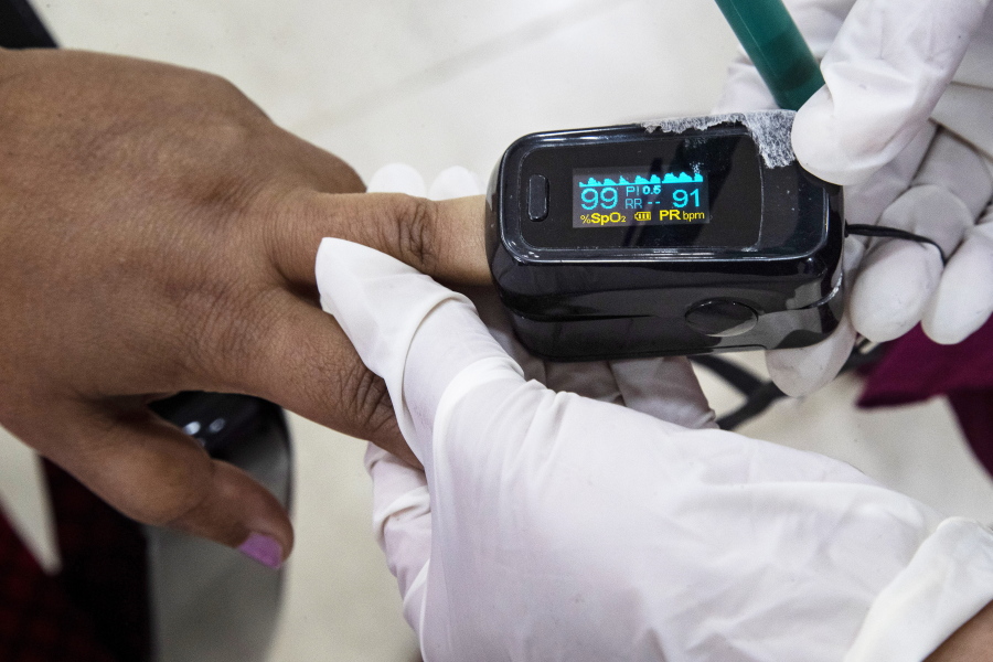 FILE - A health worker uses a pulse oximeter to check the oxygen saturation level of another after administering COVID-19 vaccine at a hospital in Gauhati, India, Jan. 21, 2021. The clip-on devices that use light to try to determine levels of oxygen in the blood are getting a closer look from U.S. regulators after recent studies suggest they don't work as well for patients of color.