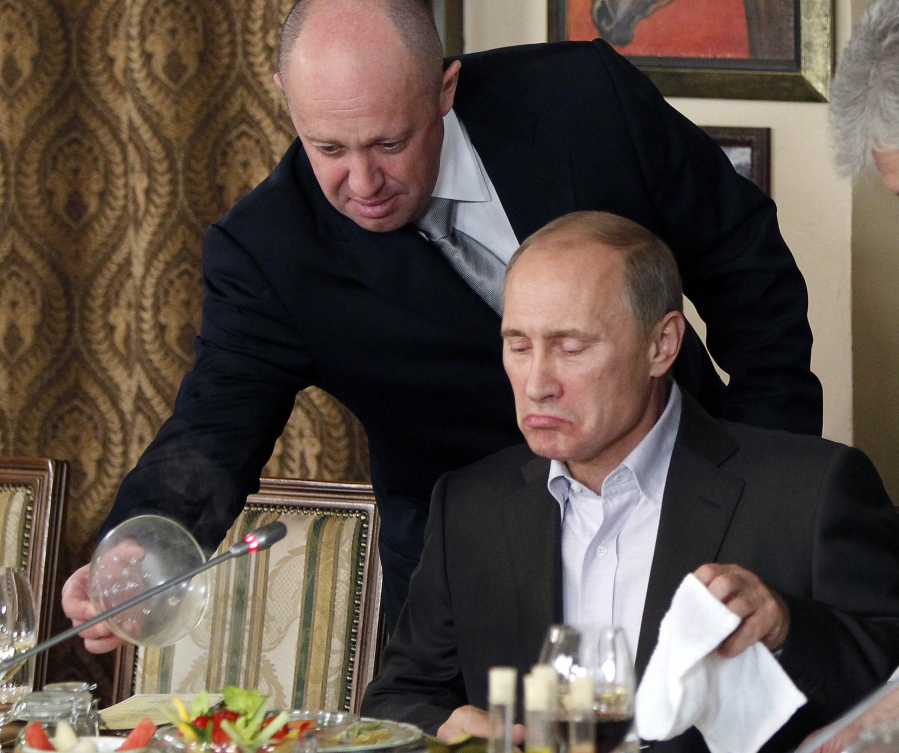 FILE - Yevgeny Prigozhin, top, serves food to then-Russian Prime Minister Vladimir Putin at Prigozhin's restaurant outside Moscow, Russia in Nov. 11, 2011. Kremlin-connected businessman Yevgeny Prigozhin kept a low profile over the years, but he has been increasingly in the spotlight recently. He has admitted that he is behind the Russian mercenary force that reportedly has been involved in conflicts around the world, including Ukraine.