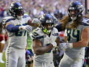 Seattle Seahawks running back Kenneth Walker III, middle, is congratulated by tight end Noah Fant, left, and tight end Colby Parkinson (84) after scoring against the Arizona Cardinals during the second half Sundayin Glendale, Ariz., Sunday.