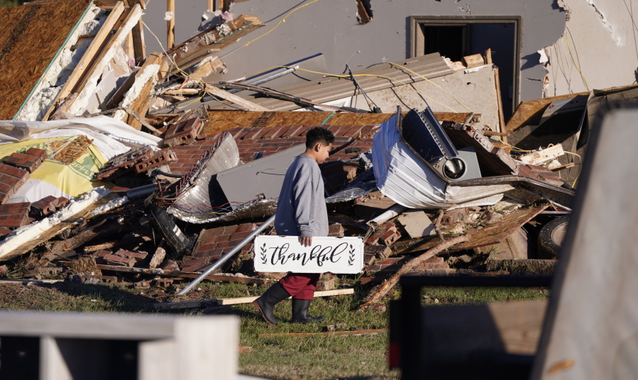Logan Johnson, 11, carries a sign that reads "Thankful" after he recovered it from his family's destroyed home after a tornado hit in Powderly, Texas, Saturday, Nov. 5, 2022.