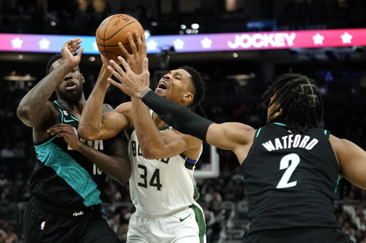 Milwaukee Bucks' Giannis Antetokounmpo (34) is fouled as he drives to the basket between Portland Trail Blazers' Nassir Little, left, and Trendon Watford (2) during the second half of an NBA basketball game Monday, Nov. 21, 2022, in Milwaukee.