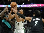 Milwaukee Bucks' Giannis Antetokounmpo (34) is fouled as he drives to the basket between Portland Trail Blazers' Nassir Little, left, and Trendon Watford (2) during the second half of an NBA basketball game Monday, Nov. 21, 2022, in Milwaukee.